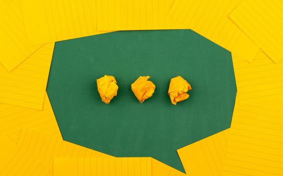 illustration of a green chat bubble against a yello background with yellow round objects in the middle portraying a "person is writing" prompt.