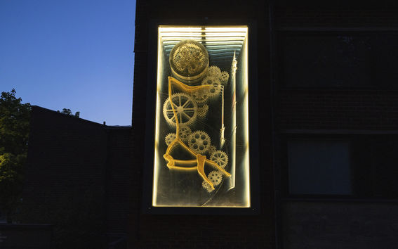 Pekka and Teija Isorättyä's artwork Lovegear on the façade of K2 building at night. The artwork is a cinetic sculpture that creates the illusion of continuing inside through the wall.
