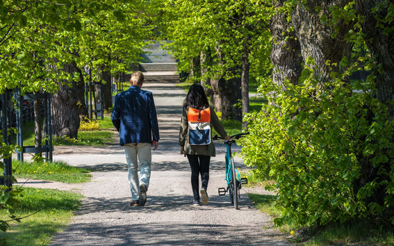 Two people walking in a tree-lined alley in Otaniemi