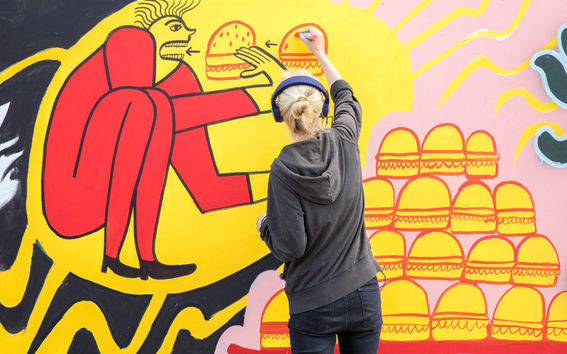 A student creating a wall mural at Aalto University campus