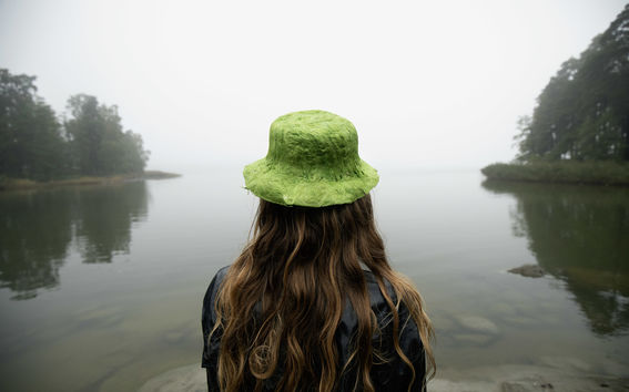 Person standing in the nature wearing a hat made out of seaweed.