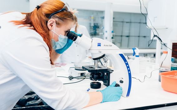Punahiuksinen nainen tutkii m´biomateriaaleja mikroskoopin avulla Aalto-yliopiston laboratoriossa. .