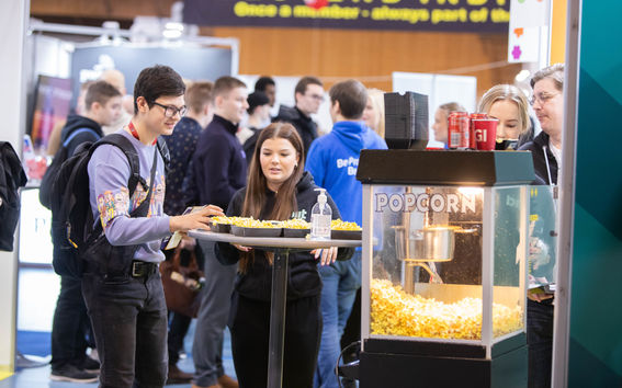 Student and company representative talking over a popcorn machine, crowds in the background