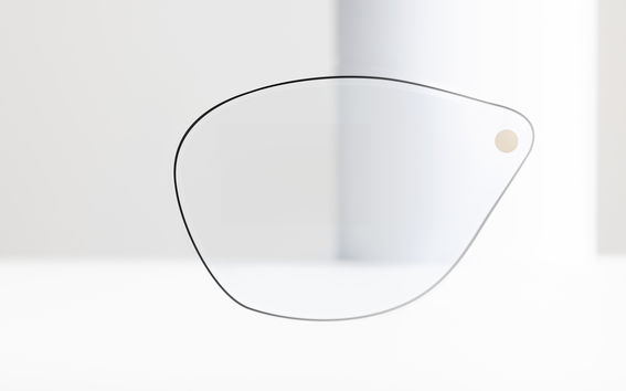 A glasses lens stands upright against a white background.