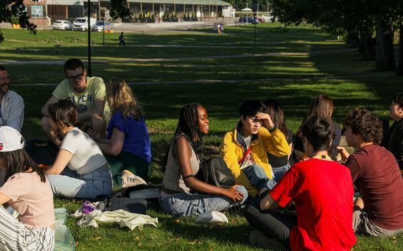 Aalto-yliopiston kesäkoulun opiskelijat viettämässä aikaa yliopiston kampuksen ulkopuolessa oleva puistossa.
