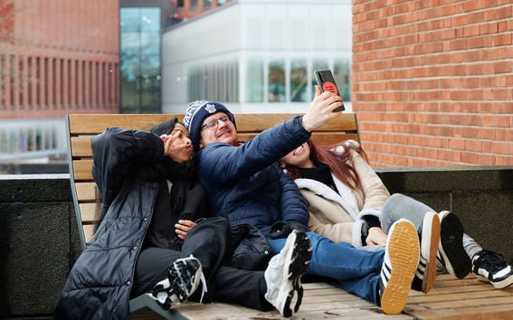 Students taking a selfie outside on campus in Autumn