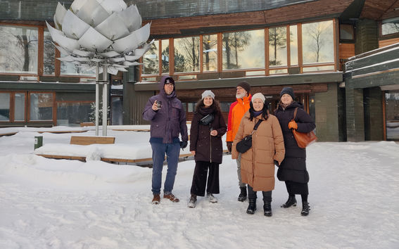 Researchers in front of Dipoli in a snowy landscape in Otaniemi 