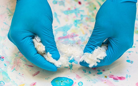White Ioncell-F fibre being handled over a colourful cellulose aquarelle.