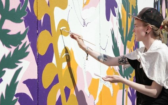Opiskelijoiden kuvittama satametrinen muraali valmistuu Flow'hun. Juliana Hyrri maalaa. Kuva: Aalto-yliopisto.