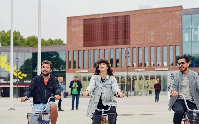 Students riding bikes in front of the Aalto University Väre building, photo by Unto Rautio