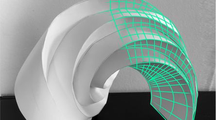 A white paper sculpture of curved arches with a green grid pattern on the right side, illustrating a transition from physical to digital realm. The sculpture is on a black surface and has a white wall as a background. The light source is on the left side, creating shadows on the right side of the sculpture.