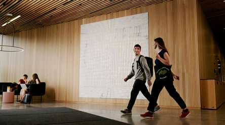 Two people walking in the School of Business