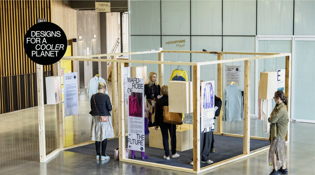 People gathering around a wooden structure as part of an exhibition in Väre building lobby.