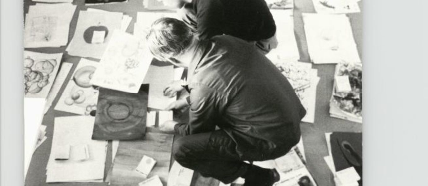 Kolme henkilöä tutkii lattialle pinottuja piirustuksia Taideteollisessa korkeakoulussa 1960-luvulla.. Kuva: Aalto-yliopiston arkisto.