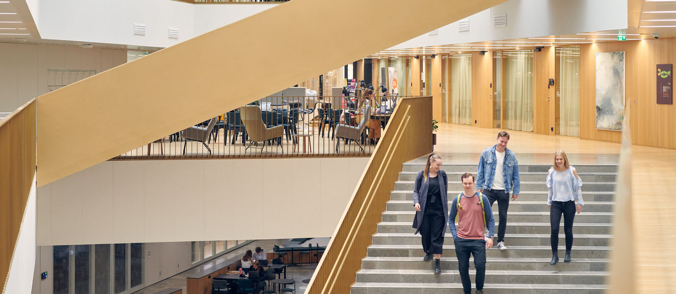 Neljä opiskelijaa laskeutuu portaita valoisassa aulatilassa kampuksella. Kuva: Aalto-yliopisto / Unto Rautio.