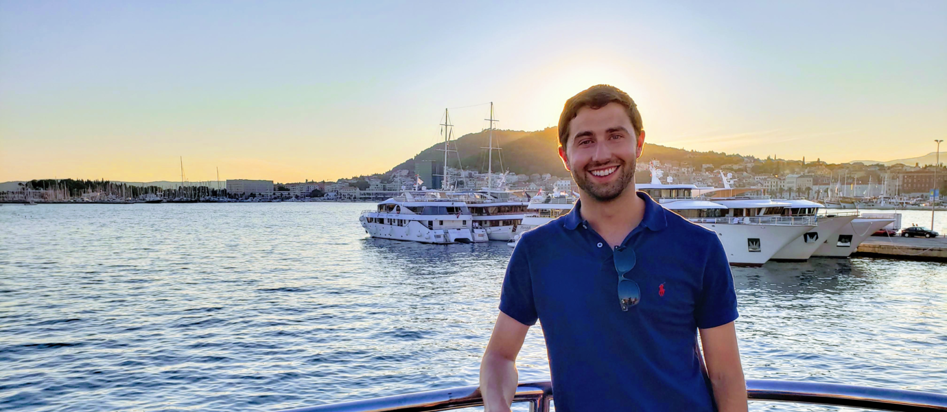 Tyler Spring standing in a harbour at sunset, smiling. 
