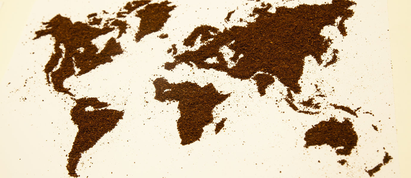 tasaiselle vaalealle pinnalle on muodostettu maailmankartta kahvijauheesta