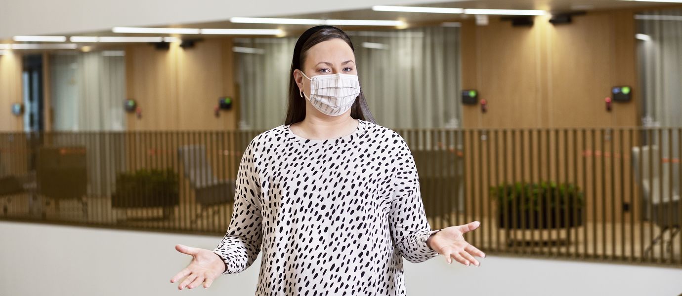 Picture of Head of Summer School Laura Sivula in a face mask and a white dress with black dots.