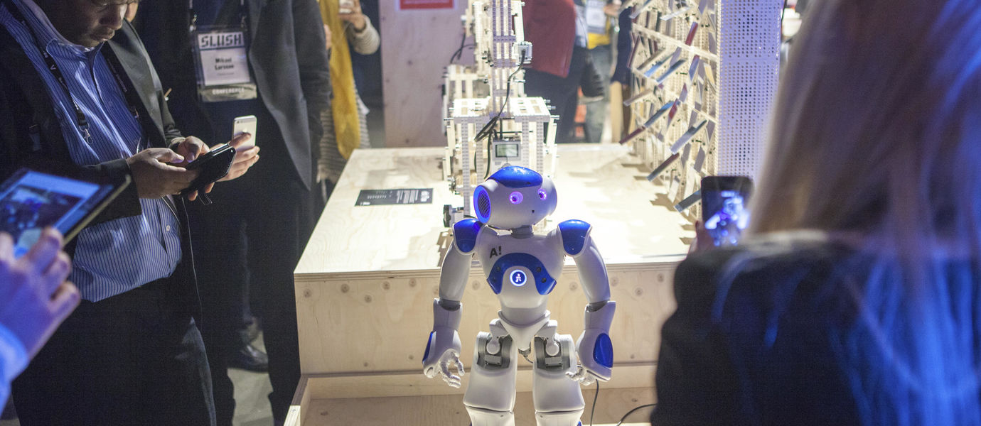 A small white and blue robot pictured on display at Aalto's monter at Slush