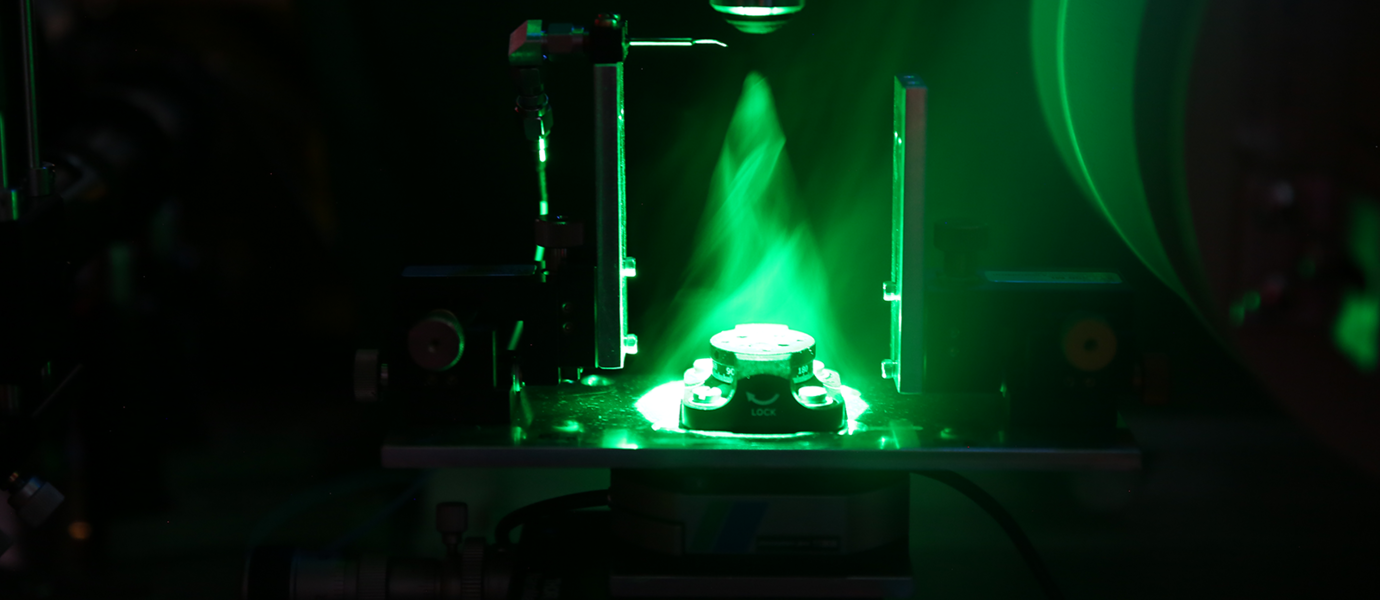 A green laser light shining on a sample stage between two magnets