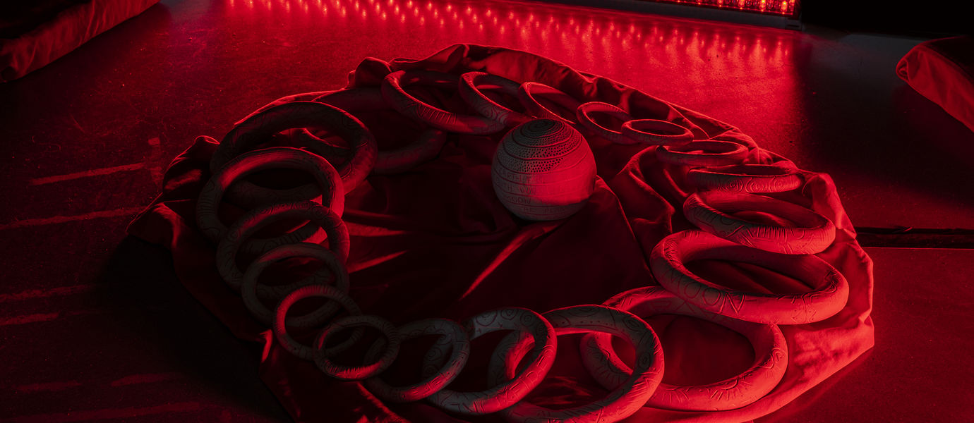 photo of installation made of ceramic circles and a ball in red light
