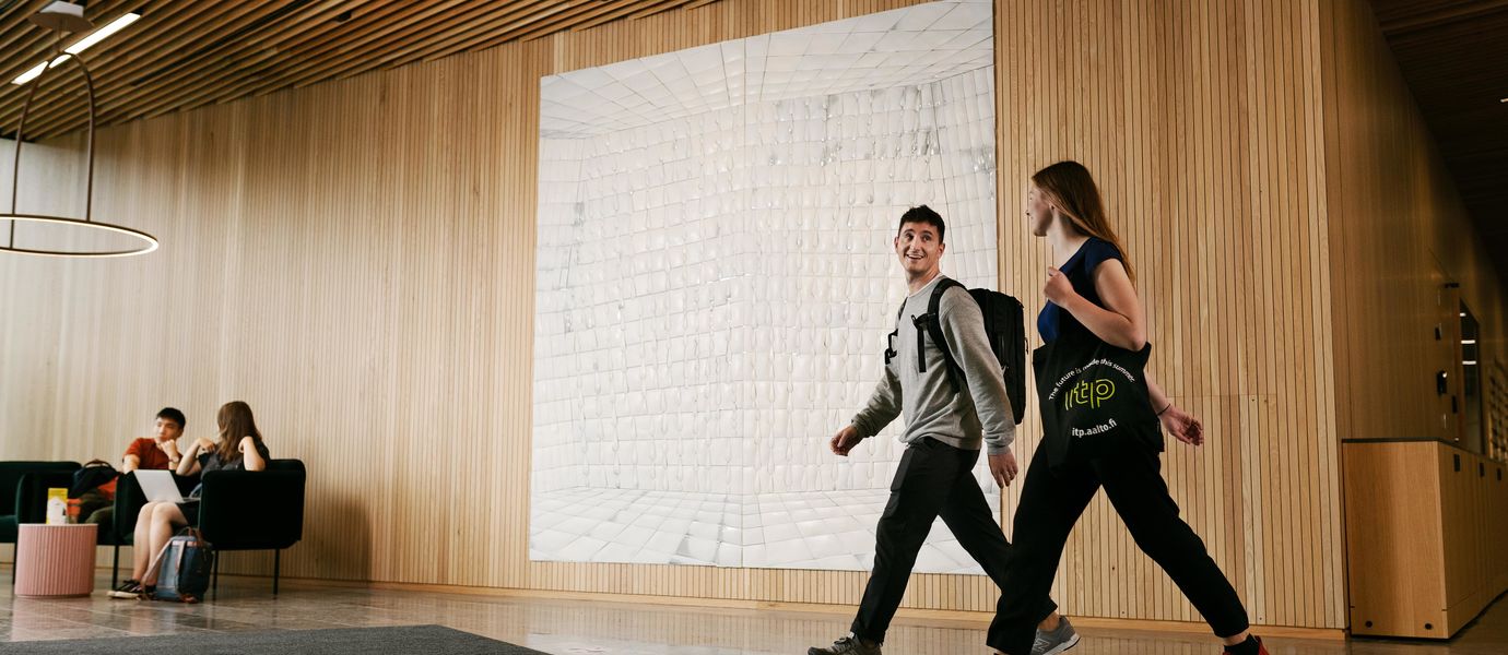 Two students walking and chatting to each other in Aalto University School of Business
