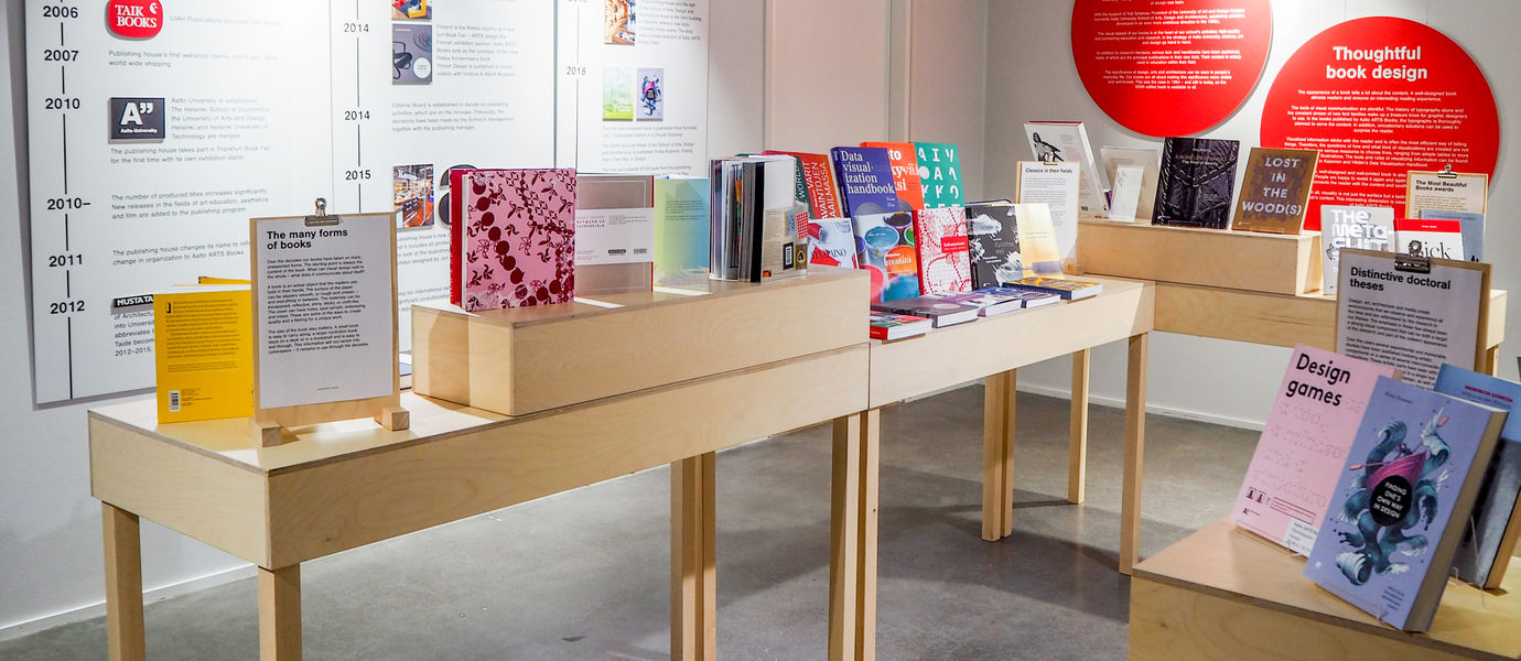 Aalto ARTS Booksin kirjoja esillä puupöydillä näyttelytilassa.
