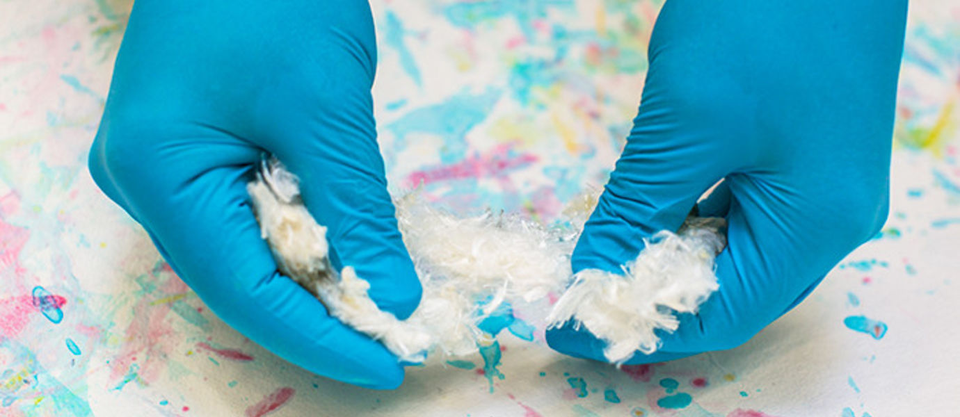 White Ioncell-F fibre being handled over a colourful cellulose aquarelle.