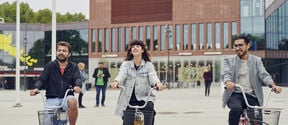 Opiskelijoita pyöräilemässä Aalto-yliopiston Väre-rakennuksen edessä kuva: Unto Rautio
