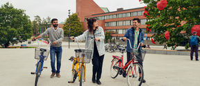 Three people with bikes in front of Väre building