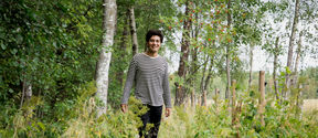 Ali Salloum walking at Laajalahti Nature Reserve in summer, surrounded by green bushes, trees and grass