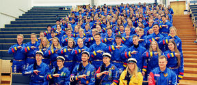 Image of lots of students wearing blue overalls and making a handsign for their guild