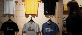Colorful Made in Aalto University -t-shirts hanging at Aalto University Shop's wall
