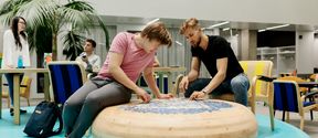 Students sitting by an interesting wooden table doing a puzzle