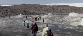Still kuva Palosuon luhytelokuvasta Talven mentyä - ajatuksia ilmastotunteista. Ihmisiä kävelemässä (selät kameraa kohti) ulkovarusteissaan jäätiköllä.