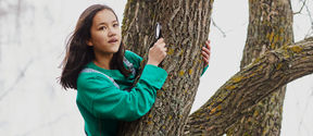 Girl sitting on a tree with a magnifying glass