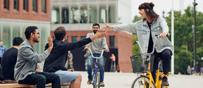 Students high-five-ing in front of the campus