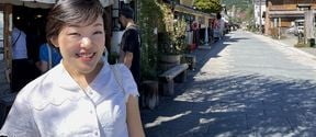 Chisako Ogiwara Digital Business Master Class alumna from Aalto University Summer School standing outside a restaurant at a street with some lush and green mountains in the background. She is wearing a short-sleeved white blouse and is smiling towards the camera.