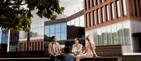 Group of student sitting on the benches outside Väre building.