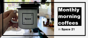 White coffee cup with Space 21 logo, space's common room on the background.