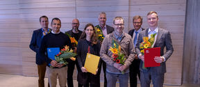 A group of eight Aalto people awarded in Aalto Day One, standing and holding flower bouquets