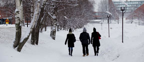 Three people walking on Otaniemi campus on a snowy day. Aalto buildings in the background. Photo: Aalto University / Mikko Raskinen.