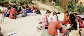 Humanitarian architects at field work in Nepal, sitting on rugs and discussing with local people