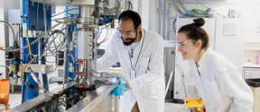 Two scientists with lab coats operating a machine