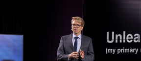 Professor Matti Sarvimäki gives a presentation on a stage.