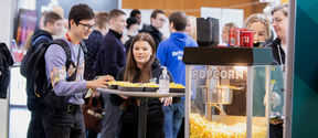 Student and company representative talking over a popcorn machine, crowds in the background