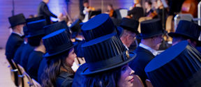 Rows of doctors sitting with their doctoral hats on, photographed from behind