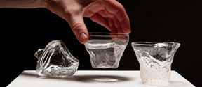 A collection of three organically shaped glasses, on of them is is being picked up by a hand