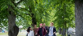 Students walking and discussing in the park area outside Aalto University campus.