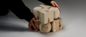 Two hands holding a cube made of 8 smaller timber cubes and spheres.